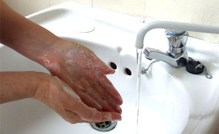 Picture of soap covered hands in a basin under a tap of running water
