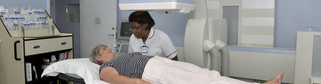 Picture of a radiologist talking to a patient who is lying on an x-ray machine bed