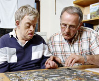 Picture of a man showing someone else how to do a jigsaw