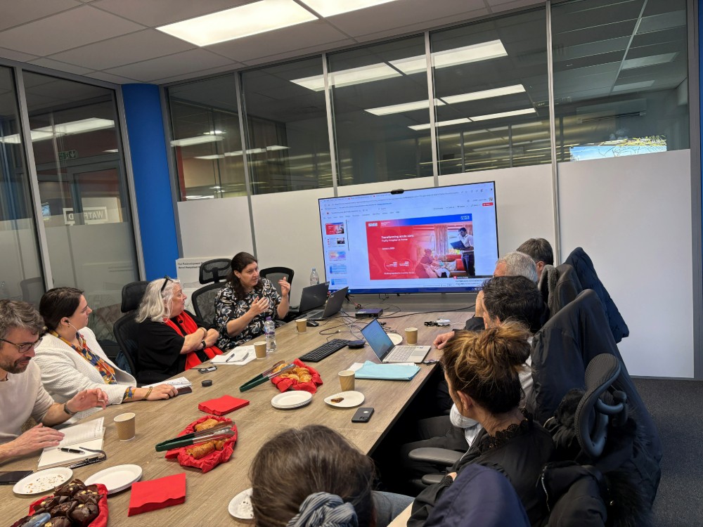 People sat around a table looking at a PowerPoint presentation on a screen