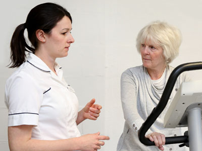 Picture of a physiotherapist talking to a patient who is on a treadmill