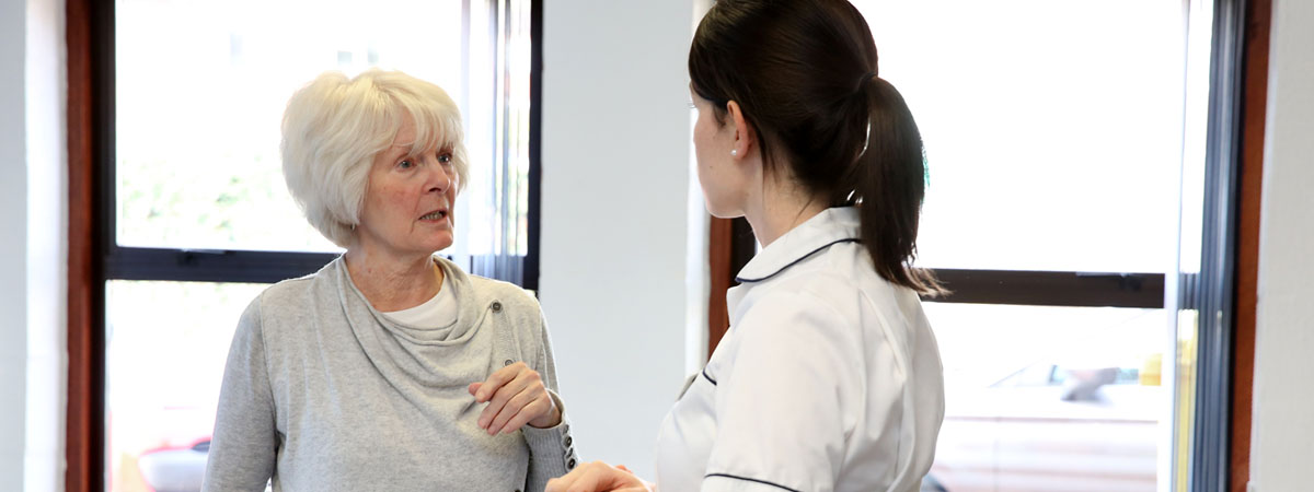 A picture of a person talking with a physiotherapist in a room