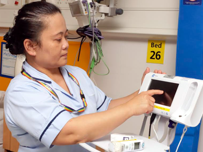 Picture of a nurse next to a machine to monitor patient vital signs