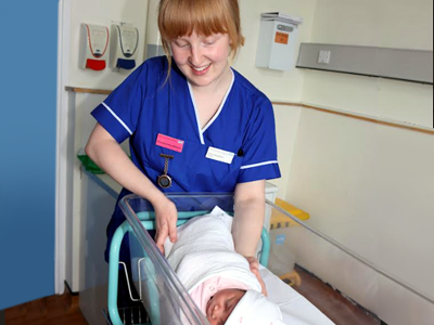 Picture of a nurse with a baby in a cot