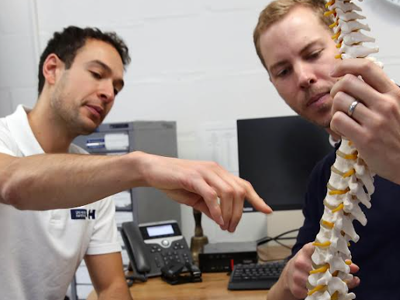 Picture of two physiotherapists who are holding a model of a human spine