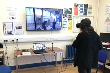 picture shows a junior doctor using a headset to take part in virtual reality simulation