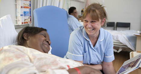 Picture of a patient in a hospital bed talking to a nurse